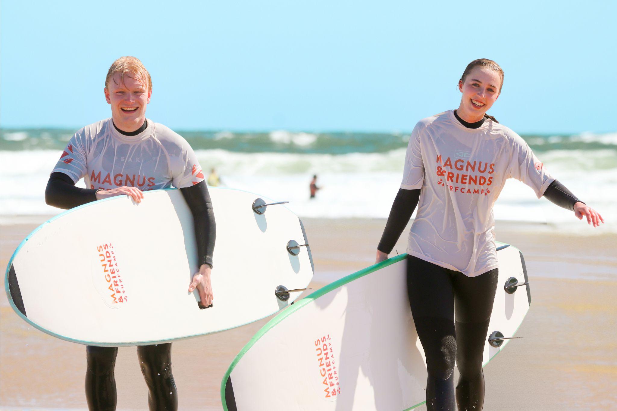 Två glada studenter som surfar mellan tentaperioderna i Baleal, Portugal
